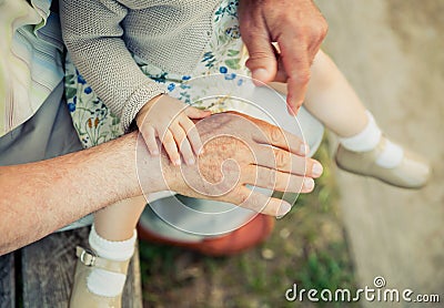 Baby girl touching hand of senior man Stock Photo