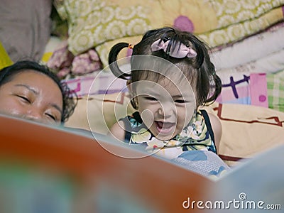 A baby girl, 2 years old, reading aloud, repeating after her auntie, a bedtime story Stock Photo