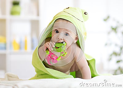 Baby with green towel after the bath biting toy Stock Photo