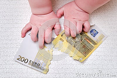 Baby hand and torn money in euros, close-up. Children fingers and an object on a white background Stock Photo