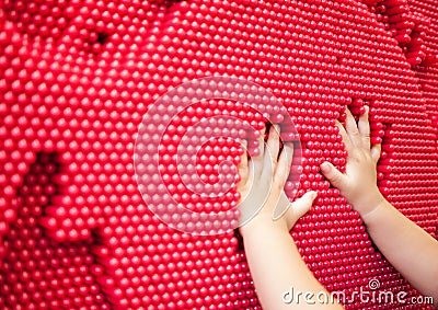 Baby hands making handprint on the red pin toy Stock Photo