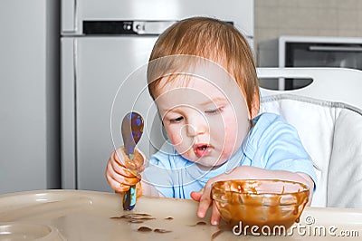 Baby in highchair covered in fruit, vegetable puree close-up. Complementary feeding tredhead oddler concept Stock Photo