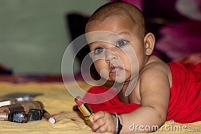 Baby infant cute holding lipstick with blurred background Stock Photo