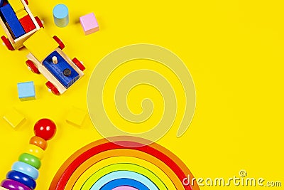 Baby kid toys background. Wooden toy train, wood rainbow and colorful blocks on yellow background. Top view, flat lay Stock Photo