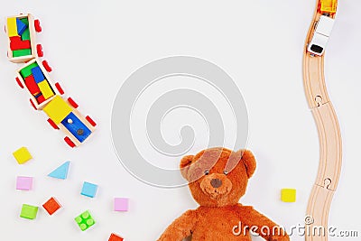 Baby kids toys background. Teddy bear, wooden train, colorful bricks on white table Stock Photo