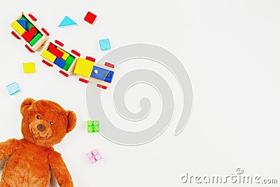 Baby kids toys background. Teddy bear, wooden train, colorful bricks on white table Stock Photo