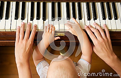 Baby learning to play piano with mother Stock Photo