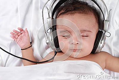 Baby listening to music with headphones Stock Photo