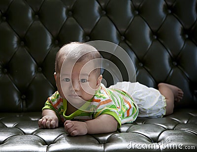 Baby lying on sofa bed with eyes contact to camera Stock Photo