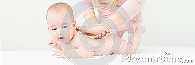 Baby massage banner. Young therapist giving a baby boy a back massage. Baby massage concept on white background with copy space. Stock Photo
