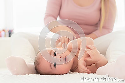 Baby massage. Female therapist gently massaging newborn baby boy. Mother applying body lotion to her infant baby boy. Stock Photo