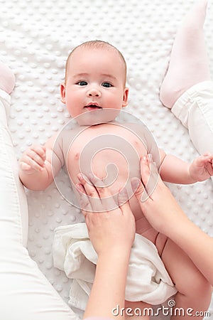 Baby massage. Female therapist gently massaging newborn baby boy. Mother applying body lotion to her infant baby boy. Stock Photo