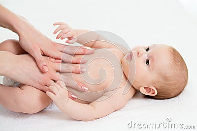 Baby massage. Mom massaging child belly. Treatment of colic Stock Photo