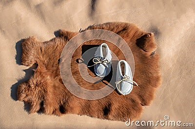 Baby moccasins displayed on a rabbit pelt and leather. Stock Photo