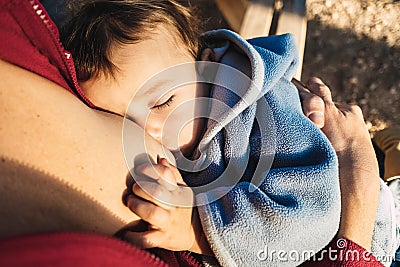 Baby naps while being breastfed by his mother outdoors Stock Photo