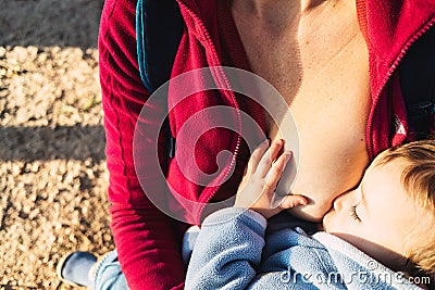 Baby naps while being breastfed by his mother outdoors Stock Photo