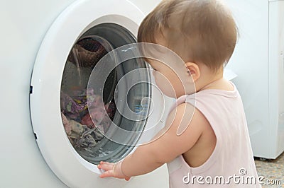 Baby near washing machine, having fun and playing with washer Stock Photo
