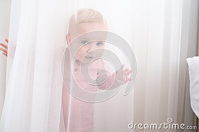 baby playing and hiding with white curtains Stock Photo