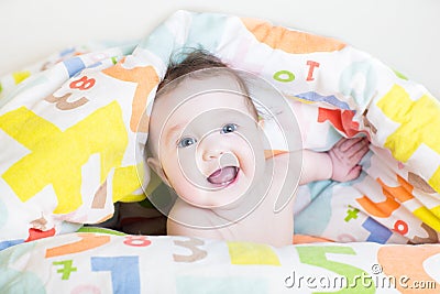 Baby playing peek-a-boo under colorful blanket Stock Photo