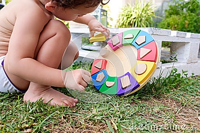 A baby plays with an entertaining didactic activity in the garden of his house in summer Stock Photo