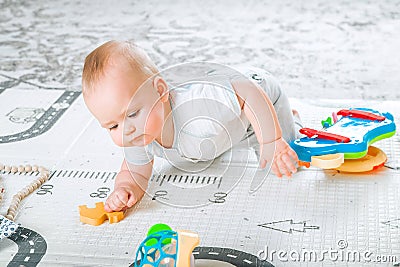 Baby plays on floor with educational toys, rattles and teething toys. Crawling babies at 8 months Stock Photo