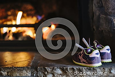 Purple sneakers heating on a fire place Stock Photo