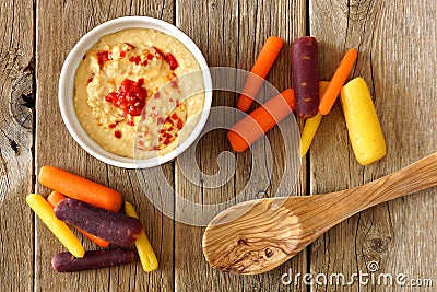 Baby rainbow carrots with hummus, overhead view on rustic wood Stock Photo