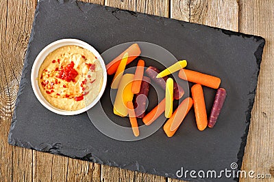 Baby rainbow carrots with hummus on slate server Stock Photo