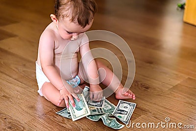 Baby reaching some dollar bills, wasted family savings concept Stock Photo
