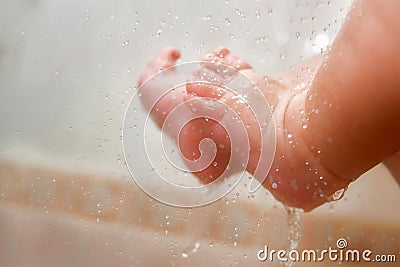 Baby`s Feet Under The Shower With Lots Of Drops. Baby`s Ankle In The Water. Parents Wash Their Child`s Feet Closeup. New Born Stock Photo