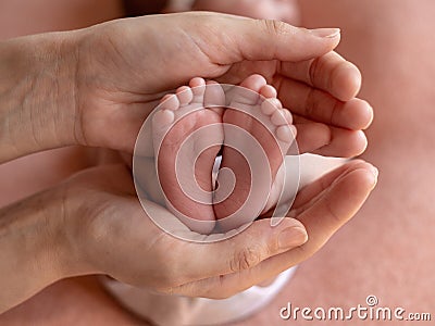 The baby`s legs are in the hands of the mother. Close-up. Heels and toes. Stock Photo