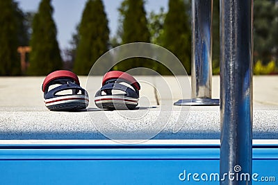 Baby sandals at the edge of swimming pool Stock Photo