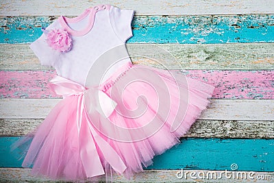 Baby set - pink tulle skirt, white bodysuit of hearts and a beautiful pink headband over pastel wooden background. Top Stock Photo