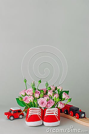 Baby shoes filled with rose flowers and toys Stock Photo