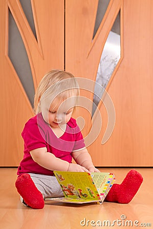 Baby sit on floor and read baby book Stock Photo