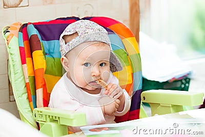 Baby sit in highchair and eats Stock Photo