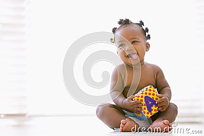 Baby sitting indoors with block smiling Stock Photo