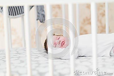 The baby sleeps in the crib. Charming girl sleeps in a bed for sleep, attached to the bed of parents. A small child having a nap Stock Photo