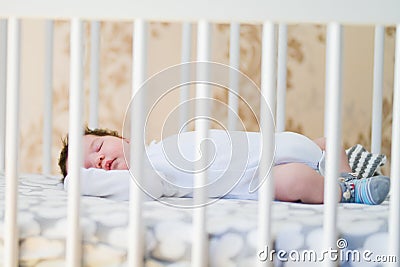 The baby sleeps in the crib. A charming baby sleeps in a crib for sleeping attached to the bed of the parents. A small child Stock Photo