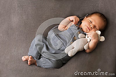 A baby sleeps hugging his little knitted bear Stock Photo