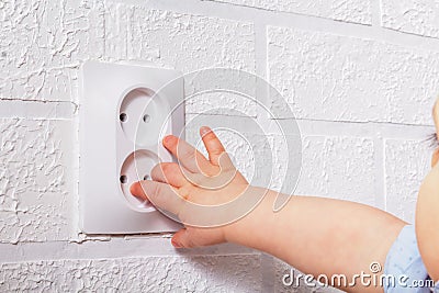 Baby small hand near electrical socket. Close-up. Stock Photo