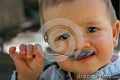 Baby with spoon in his mouth Stock Photo