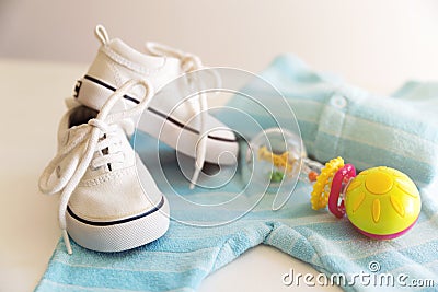 Baby stuff is on a white background. Things for little boy, rattle and shoes. Newborn baby necessities. Stock Photo