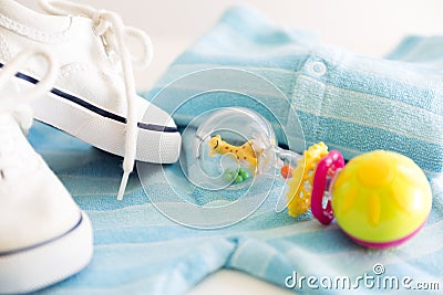 Baby stuff is on a white background. Things for little boy, rattle and shoes. Newborn baby necessities. Stock Photo