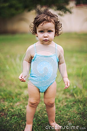 Baby in swimming suit standing in grass Stock Photo