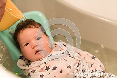 The baby is taking a bath. wrapped in a diaper. Baby having a bath in little bathtub Stock Photo