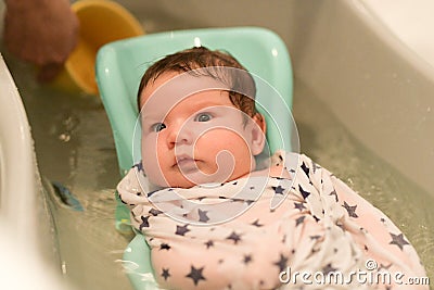 The baby is taking a bath. wrapped in a diaper. Baby having a bath in little bathtub Stock Photo