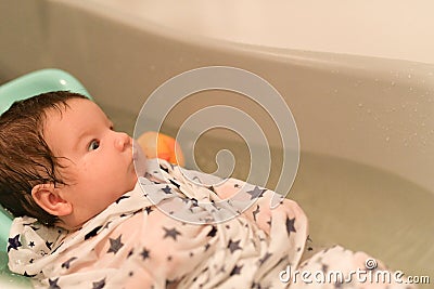 The baby is taking a bath. wrapped in a diaper. Baby having a bath in little bathtub Stock Photo