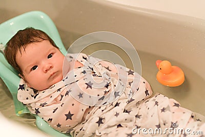 The baby is taking a bath. wrapped in a diaper. Baby having a bath in little bathtub Stock Photo