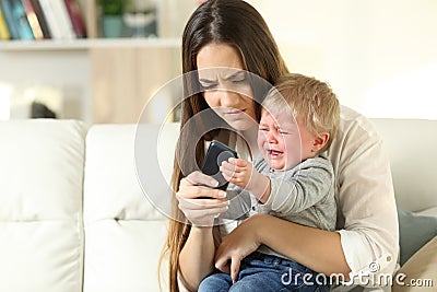 Baby tantrum fighting with his mother for a smart phone Stock Photo